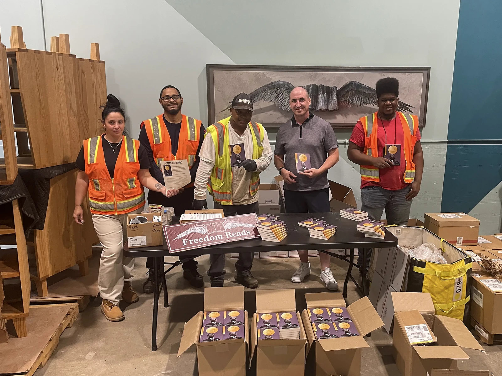 Five team members smile as they pack hundreds of copies of Martin Luther King’s “I Have A Dream” speech for delivery to incarcerated readers across the nation in honor of the speech’s 60th anniversary.