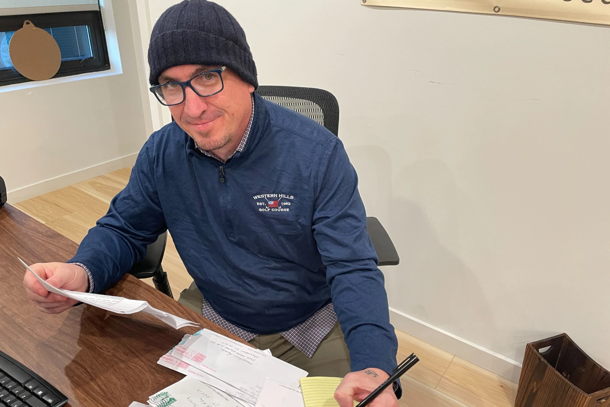 Freedom Reads Communications Manager Steven Parkhurst with kites from our Freedom Library patrons. Freedom Reads Communications Manager Steven Parkhurst sits at a desk with letters in hand, smiling at the camera.